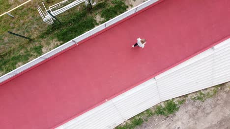 colorful-contrast-man-walking-on-red-running-track-topdown