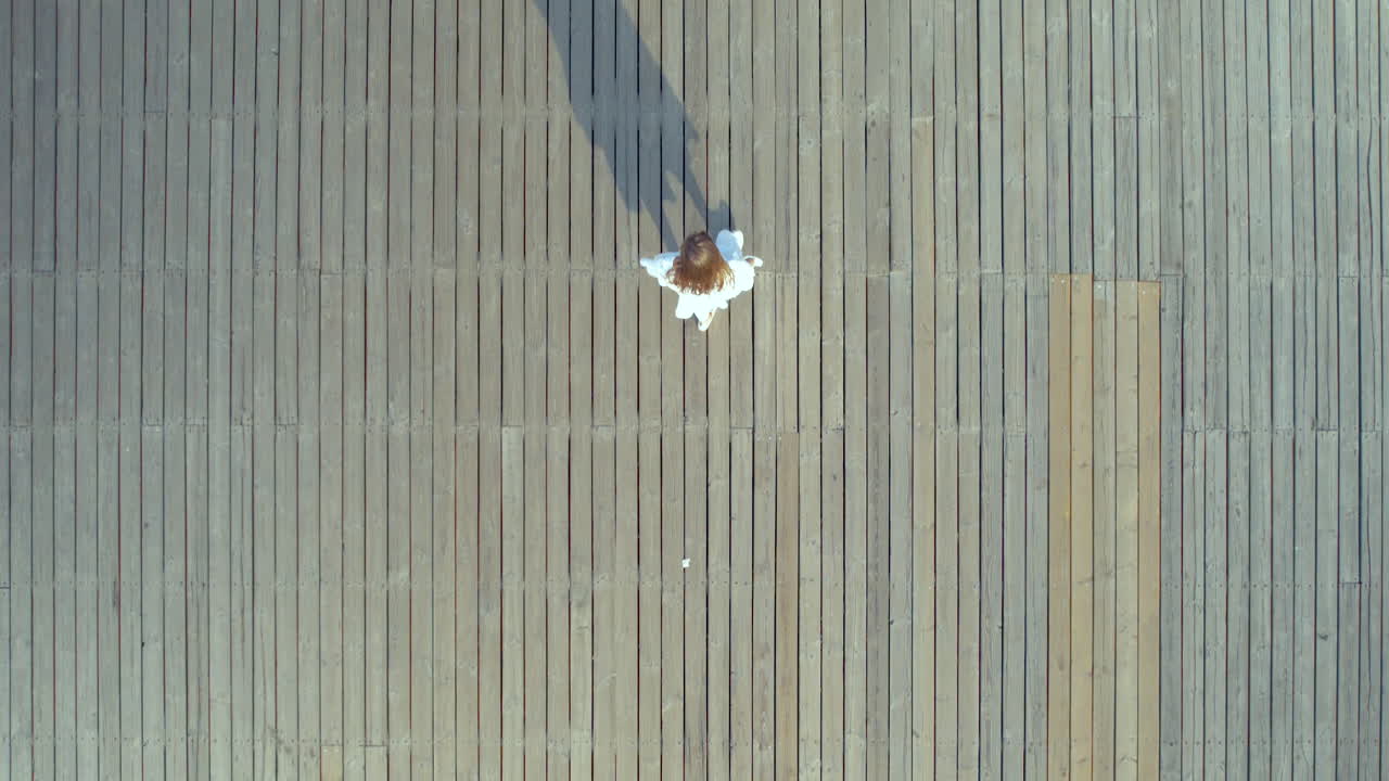 ⁇ 색 여름 드레스를 입은 예쁜 여성이 해가 뜨면 나무 기 ?? 을 따라  ⁇ 고 있습니다. orlowo, gdynia, poland - aerial tracking top down