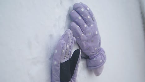 Pair of purple polka dot gloves on snow