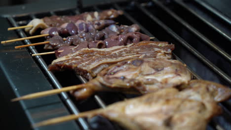 chicken thigh, liver, and heart on barbecue stick grilling with a slice of pork meat