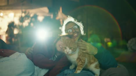 filmagem em close-up: um casal apaixonado está deitado em cadeiras de saco de feijão, acariciando um gato vermelho e vendo um filme. uma festa fora da cidade. descanso na casa de campo