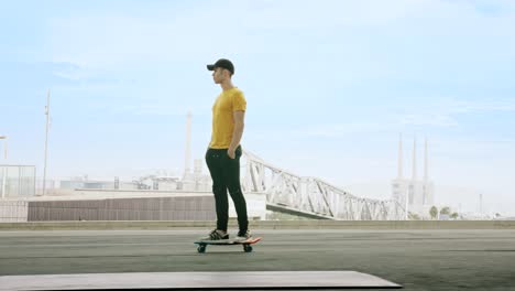 lateral view of a young attractive trendy man skateboarding fast under a solar panel on a morning sunny day with an urban city background