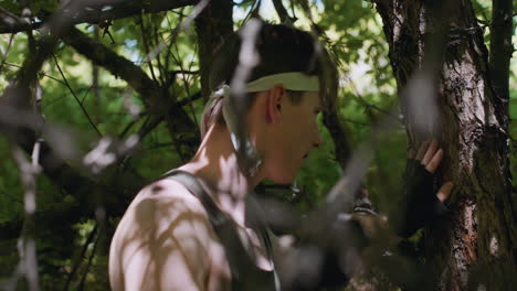dynamic side view of soldier striking tree bark with punch slap and elbow while navigating dense underbrush, headband tied, muscles tensing against rugged wood in outdoor combat training