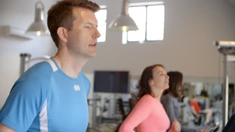 Un-Hombre-Y-Dos-Mujeres-Jóvenes-Corriendo-En-Cintas-De-Correr-En-Un-Gimnasio.