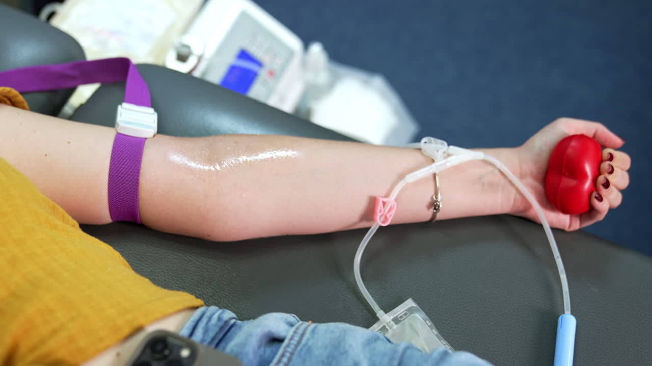Arm of unrecognized woman with a tourniquet on the forearm. Donor is pressing a red ball before giving her blood. Close up.