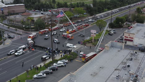 a funeral procession lead by a white hearse drives past a community mourning