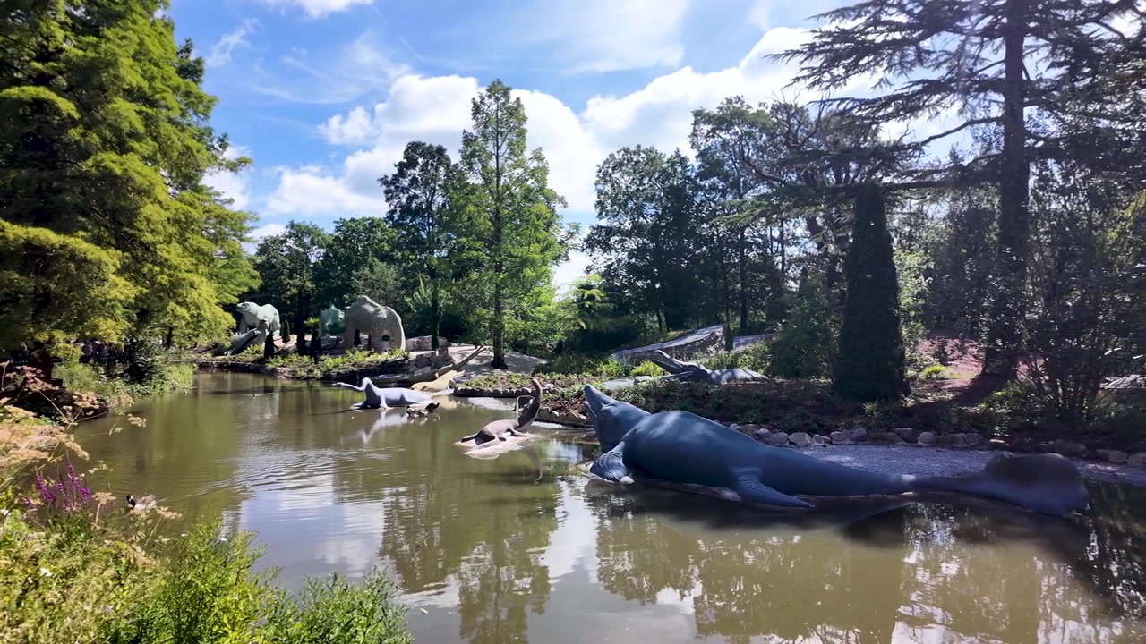 緑豊かな公園の風景の中にある象徴的なクリスタルパレスの恐竜たちの魅惑的なパンショット
