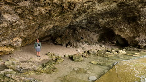 joven caminando dentro de una cueva costera en malta, vista aérea