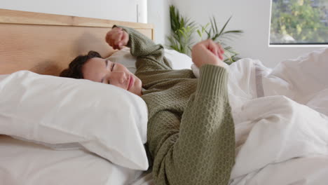 stretching in bed, woman waking up and smiling in cozy bedroom