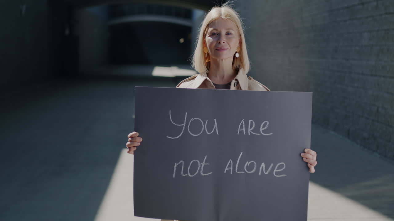 Woman Holding a Poster Saying "You Are Not Alone"