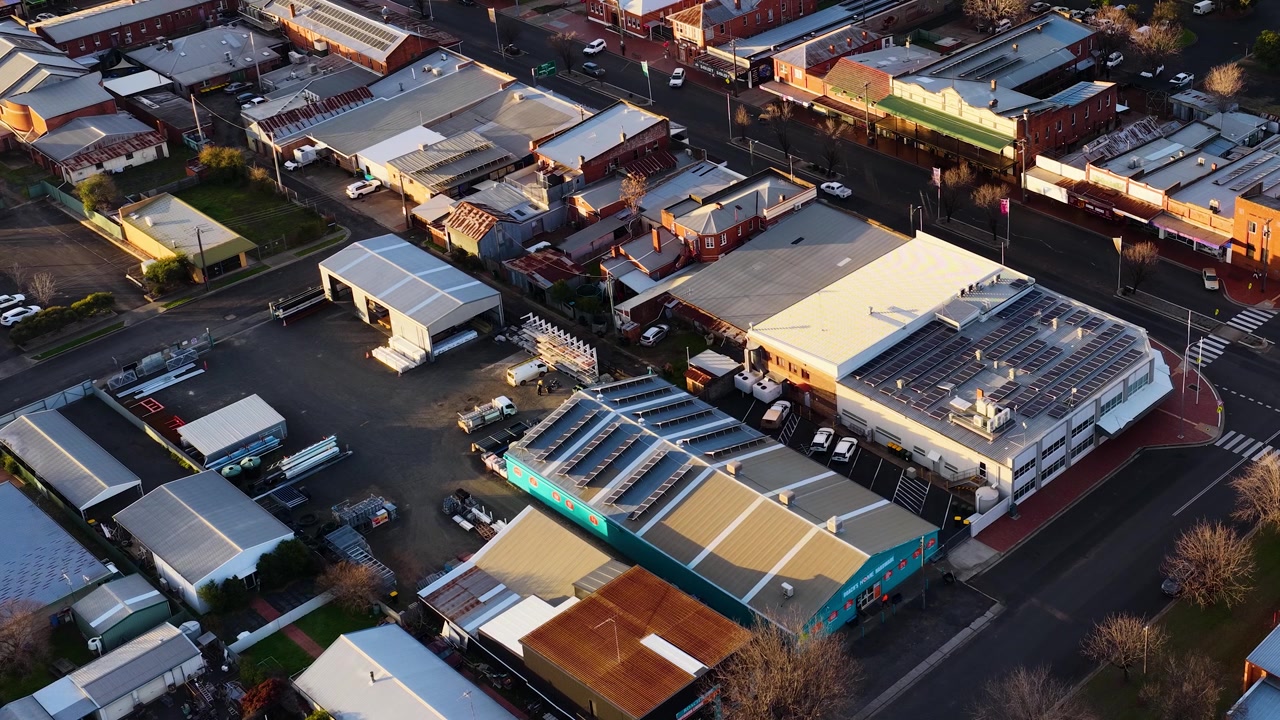 Dronebilde fra høy vinkel av kommersielle tak og gater under den gylne timen i Coonabarabran, Australia.