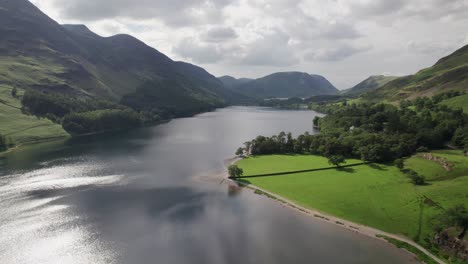 high drone shot flying backward over crummock water on a sunny day, lake district, cumbria, uk