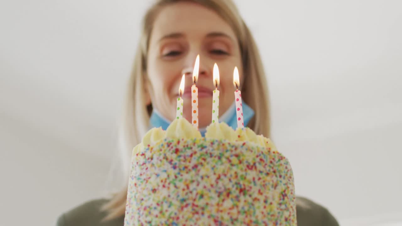 mujer soplando velas en el pastel en casa