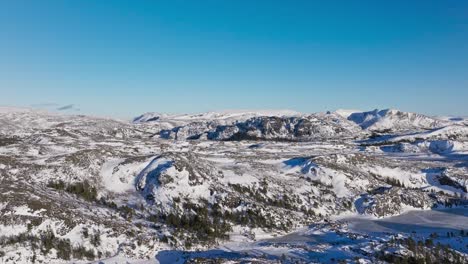 fly over snowy forest mountains near bessaker, norway