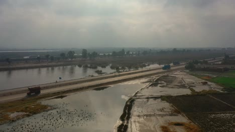 aerial view of rural farm affected by spring flooding featuring farm house, silo on dry ground, livestock, green fields, brown flood water, covered roads