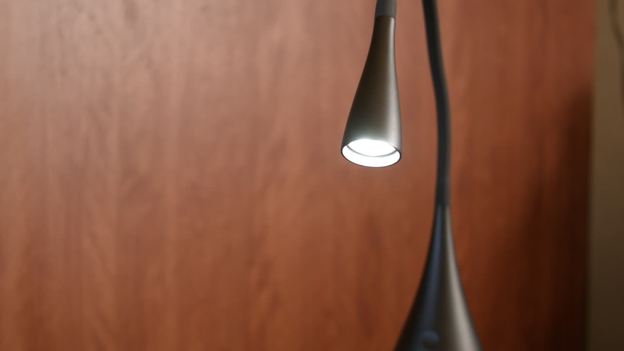 조명이 켜진 현대적인 미니멀리즘 세련된 책상 램프가 전구에 초점을 맞춥니다.