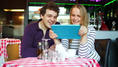 una pareja joven en un café teniendo un chat de video en una tableta pc