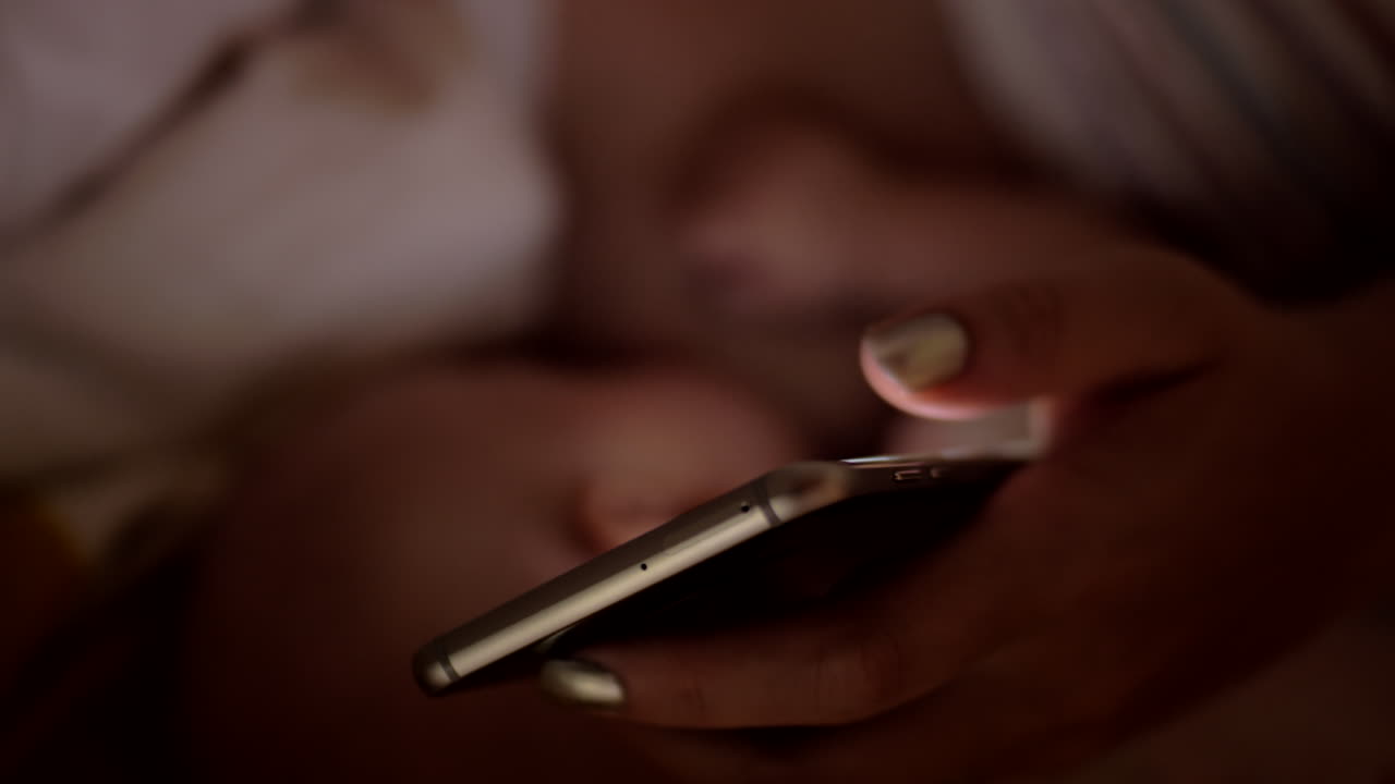 madre navegando por internet en el móvil mientras amamanta al bebé