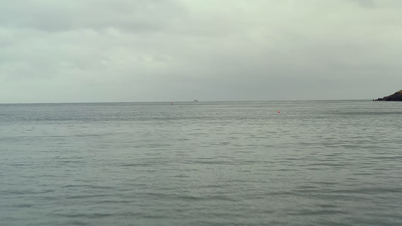 개방된 비어있는 물 위에서 공중 도리, 한 개의 시 선박이 지평선에서 멀리 떨어져, 구름이 많은 날에 조용한 조용한 물