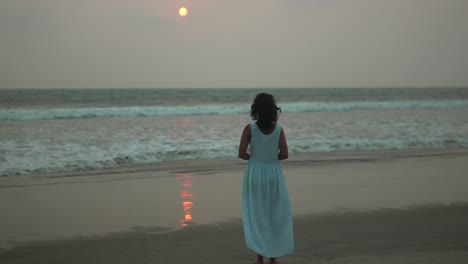 Frau-Im-Blauen-Kleid-Geht-Allein-Am-Strand-Bei-Sonnenuntergang,-Nachdenkliche-Stimmung