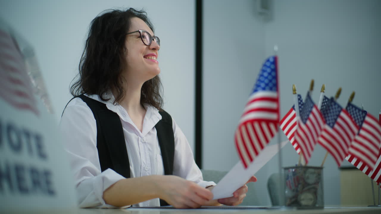 Female Polling Officer Sits at the Table Offers American Flags or Badges Female Polling Officer Sits at the Table at Polling Station Offers American Flags or Badges to Voters after Voting National Election Day in the United States of America Civic Duty and Democracy