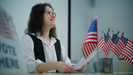 Female Polling Officer Sits at the Table Offers American Flags or Badges Female Polling Officer Sits at the Table at Polling Station Offers American Flags or Badges to Voters after Voting National Election Day in the United States of America Civic Duty and Democracy