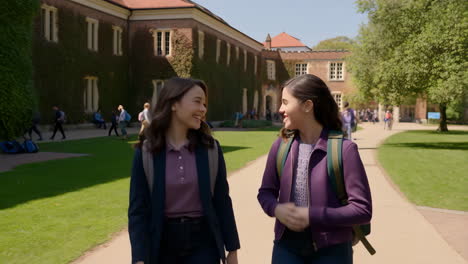 two young women students walking and smiling on a college campus