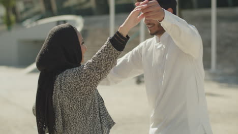 una pareja musulmana romántica bailando afuera en un día soleado.