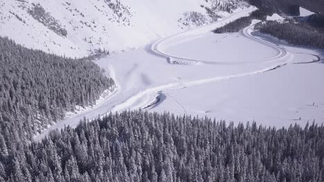 Descenso-Aéreo-De-Invierno-Frío-A-Bucle-De-Carretera-Nevada-En-La-Base-De-Una-Gran-Colina