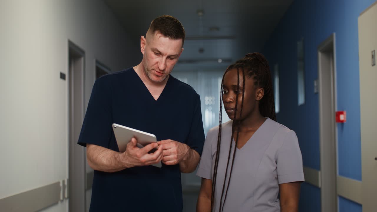 Doctors and Nurses Discussing a Patient on a Tablet in a Hospital Corridor