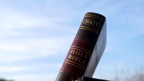 a brown holy bible standing up with the sky behind