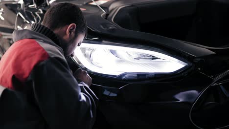 autocenter represantative attaching a plastic piece of car's bumper to the bottom side.