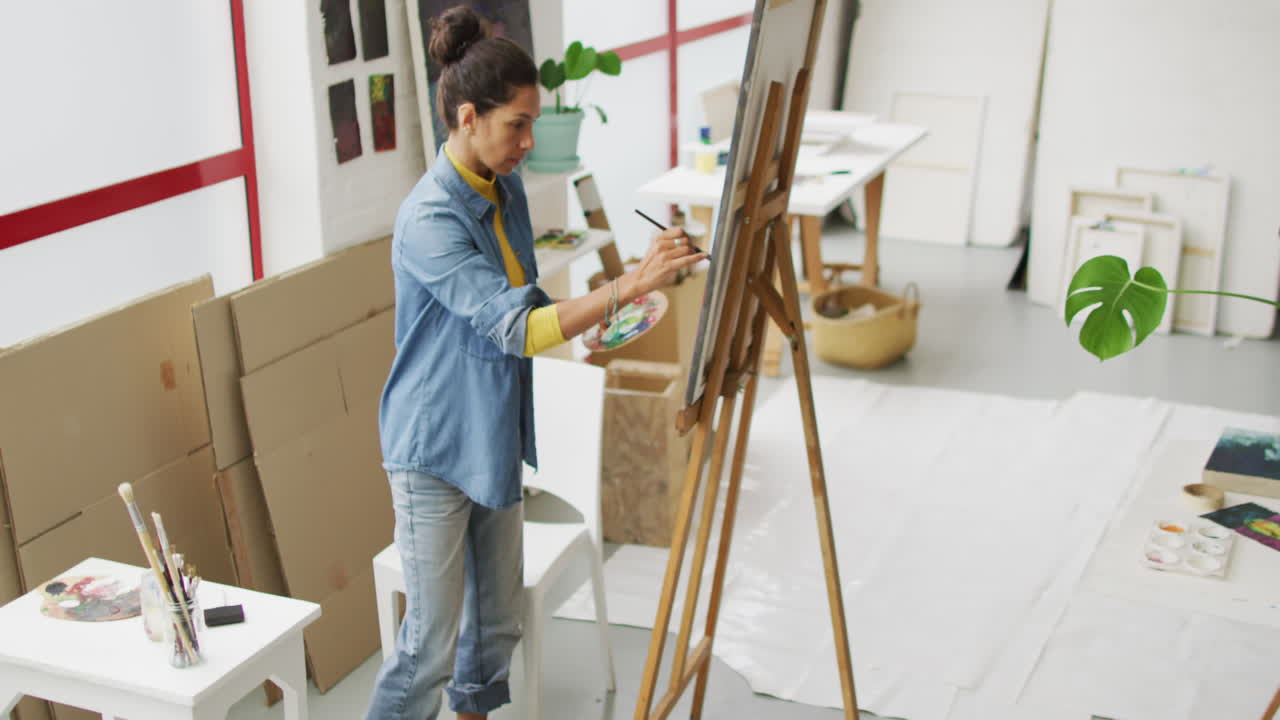 Video di un'artista donna birazziale che dipinge in studio