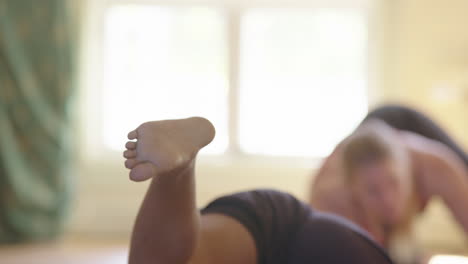 enfoque superficial en el miembro de la clase de yoga levantando la pierna de todos los cuatro, entrenamiento básico