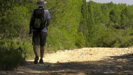 man with camera on hiking trail, stops to take photo