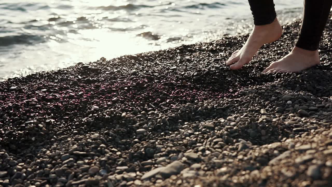 Donna che cammina a piedi nudi su una spiaggia di ciottoli