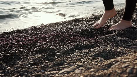 woman walking barefoot on a pebble beach