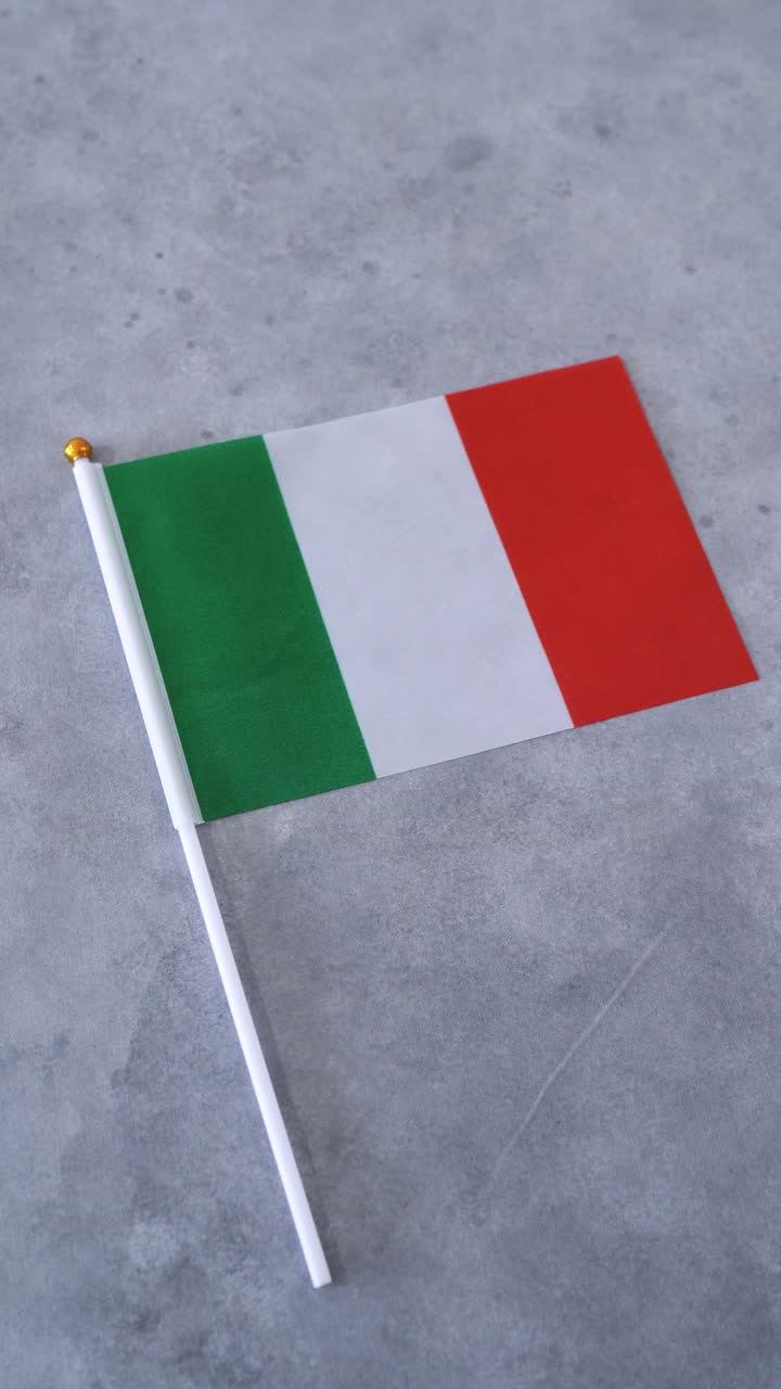 Bandiera italiana in primo piano. Scatto verticale con sfondo grigio. Bandiera nazionale italiana.