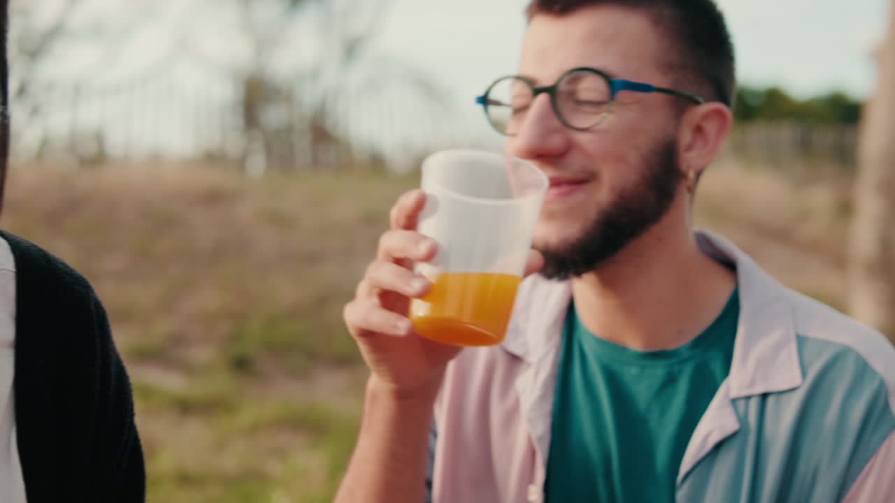 Friends Enjoying a Picnic at Sunset, focus on the young man