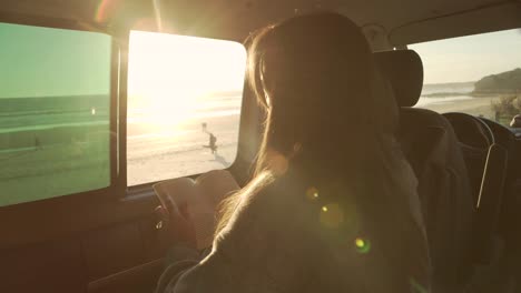 traveling woman reading book in van at sunset