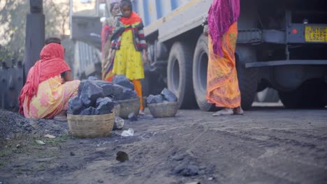 women laborers handling coal near a truck in a rural setting