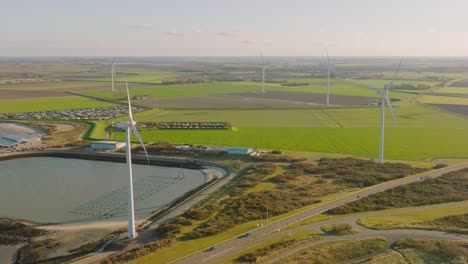 aerial slow motion shot of wind turbines and a road in a rural, coastal area of the netherlands on a beautiful sunny day