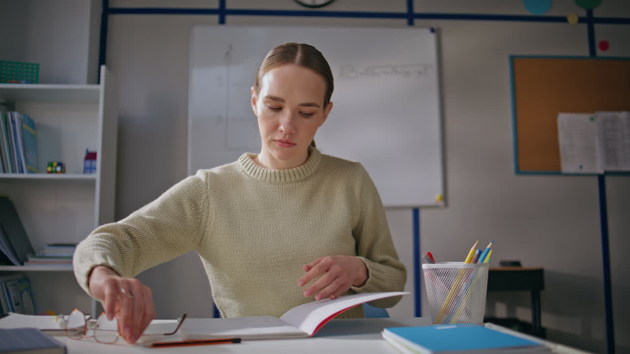 Young tutor opening notebook wearing glasses at cabinet closeup. Teacher working