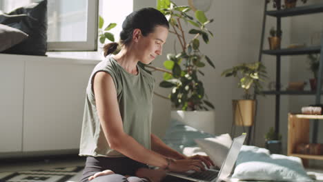 woman sitting in lotus pose and using laptop at home