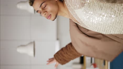 un hombre con un vestido y un abrigo de piel bailando sensualmente en la cocina, de cerca