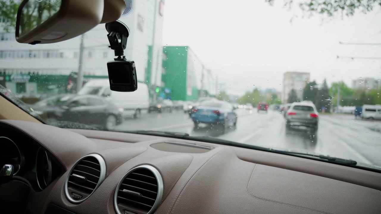 Interior view from a moving vehicle with windshield wipers clearing rainwater from the glass