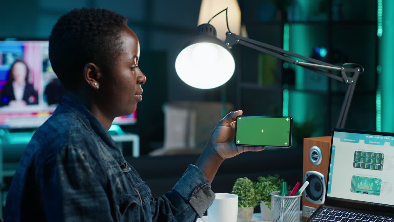 Woman reviewing data on a smartphone at night in home office