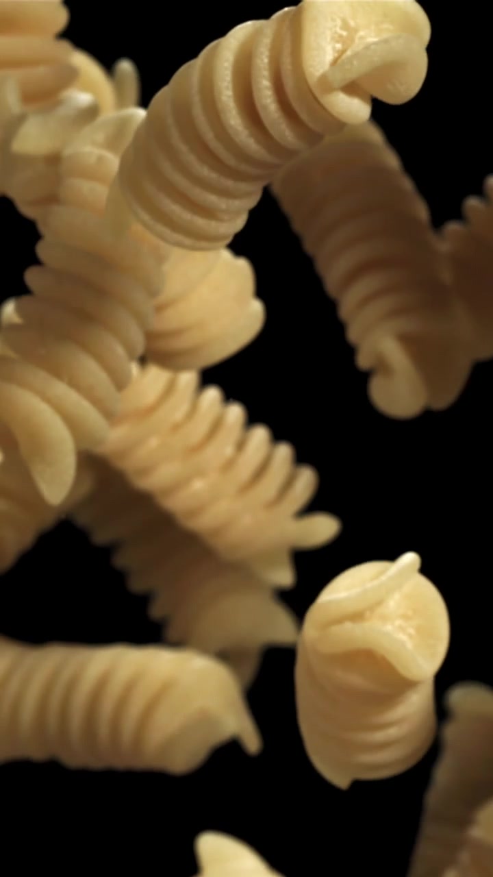 Movimento rallentato di fusilli secchi in caduta su sfondo nero