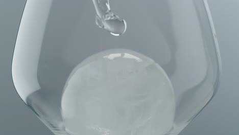 clear liquid pouring into glass with ice cubes