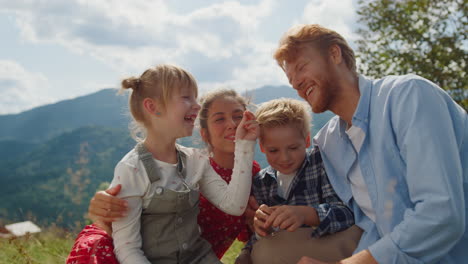 lächelnde familie, die zusammen auf der bergwiese posieren. sommerferien